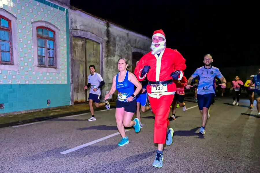 Atleta vestido de Pai Natal a correr com o pelotão.